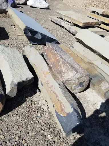 Woman in straw hat smiles, holding wine glass near a lake.