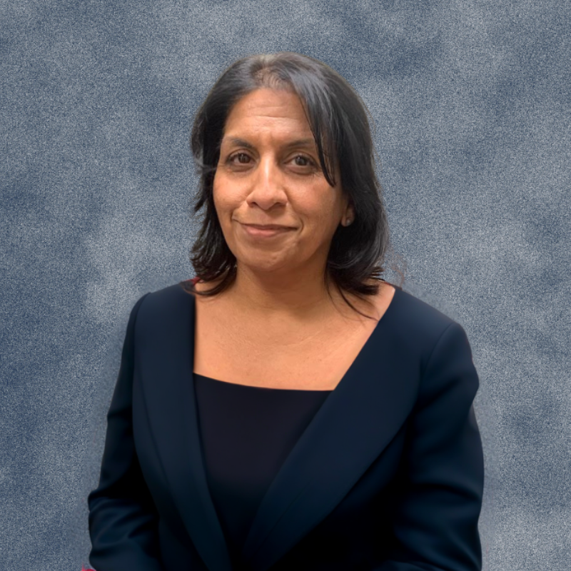 A woman in a red sweater is smiling in front of a blue background
