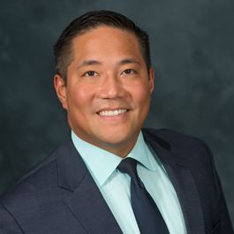 A man in a suit and tie is smiling for the camera.