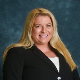 The woman is wearing a black jacket and smiling for the camera.