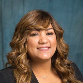 A woman with long brown hair is smiling for the camera.
