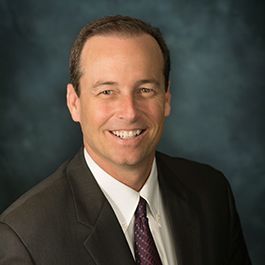 A man in a suit and tie is smiling for the camera.