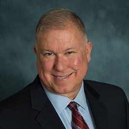A man in a suit and tie is smiling for the camera.