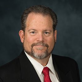 A man with a beard is wearing a suit and tie.