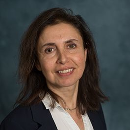 A woman in a suit and white shirt is smiling for the camera.
