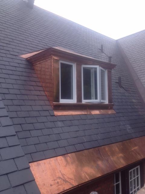 Un toit avec une fenêtre et un toit en cuivre