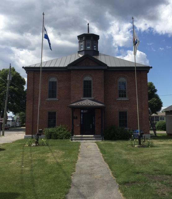 Un bâtiment en brique avec deux drapeaux devant lui