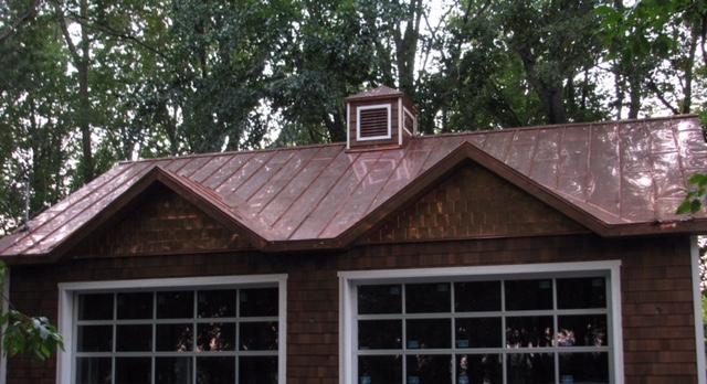 A house with a copper roof and a cupola on top of it.