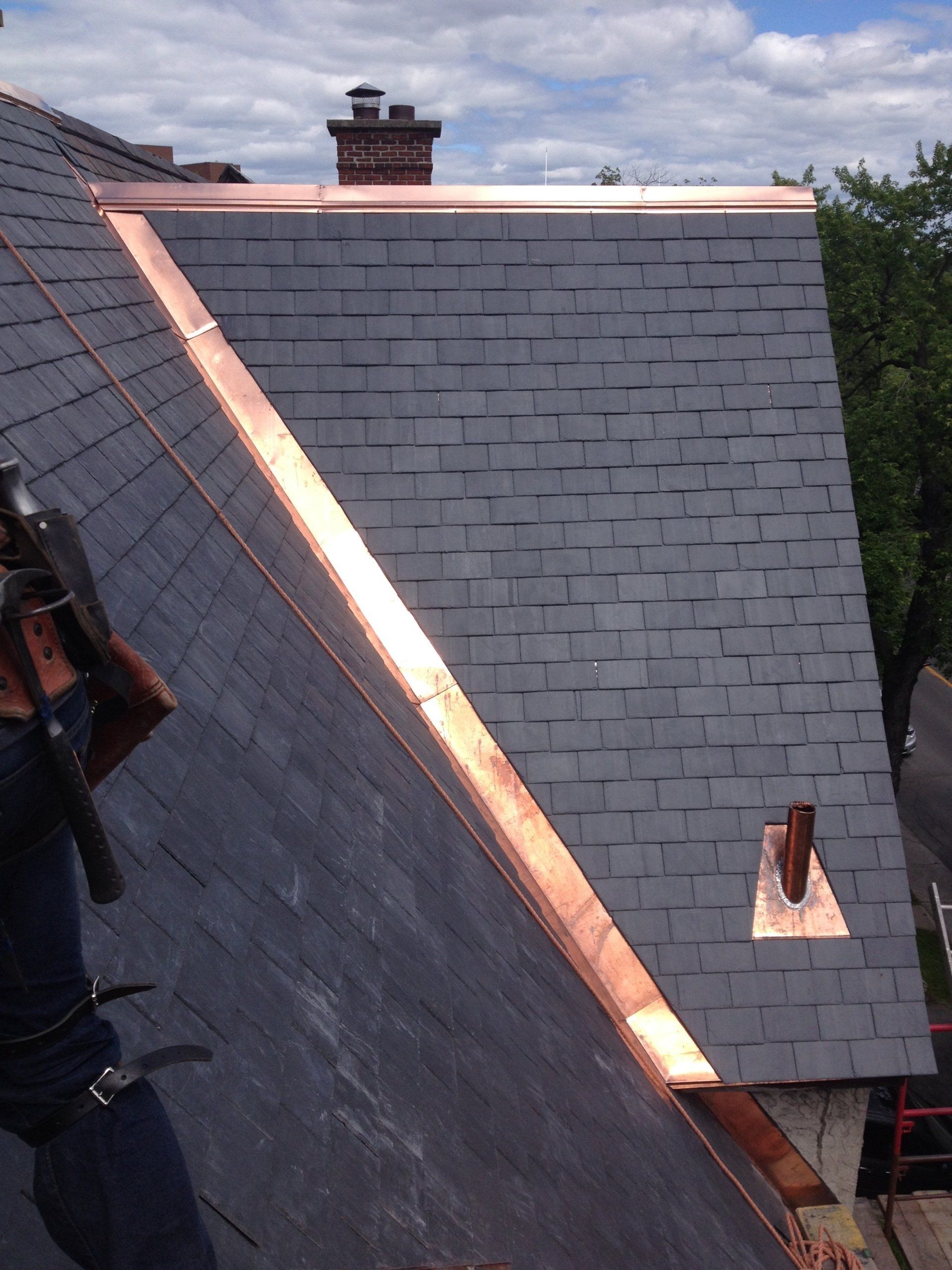 Un homme travaille sur un toit avec des garnitures en cuivre