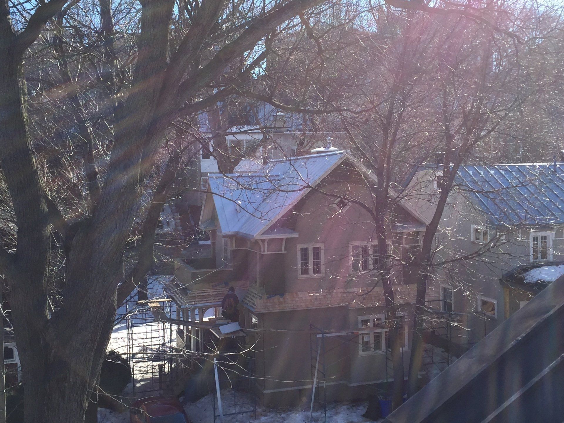 A house with snow on the roof is surrounded by trees