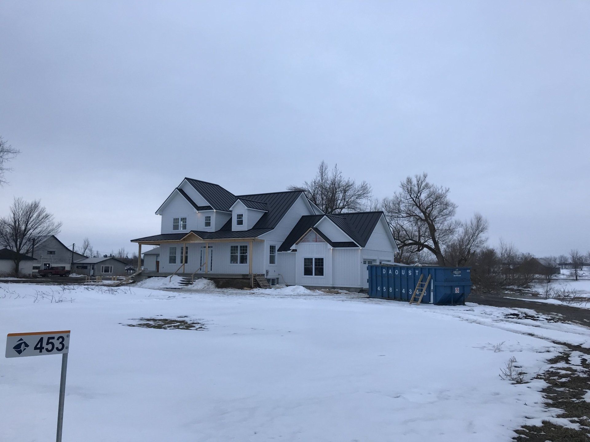Une grande maison blanche se trouve au milieu d'un champ couvert de neige.