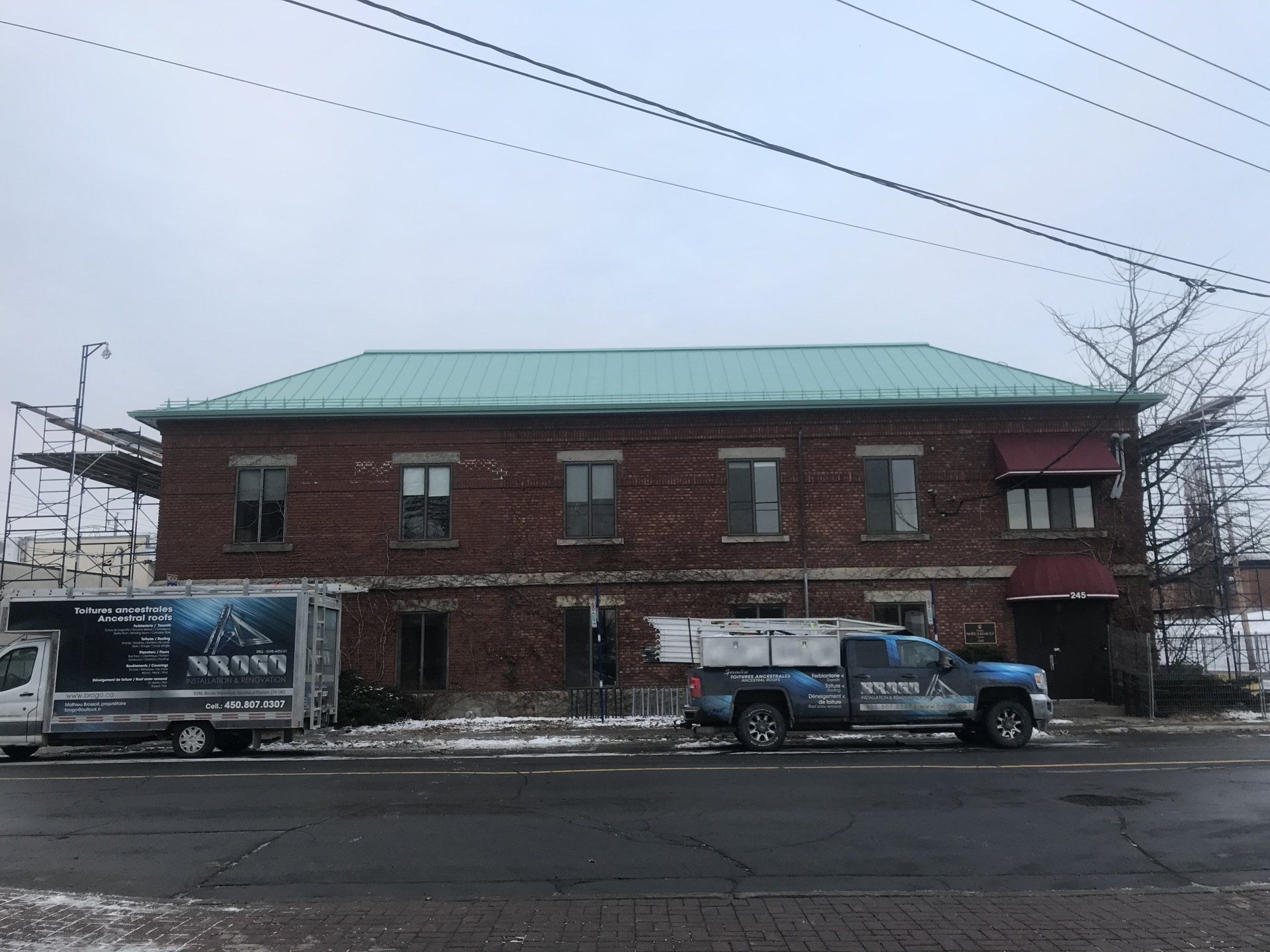 Un bâtiment en brique avec un toit vert et deux camions garés devant