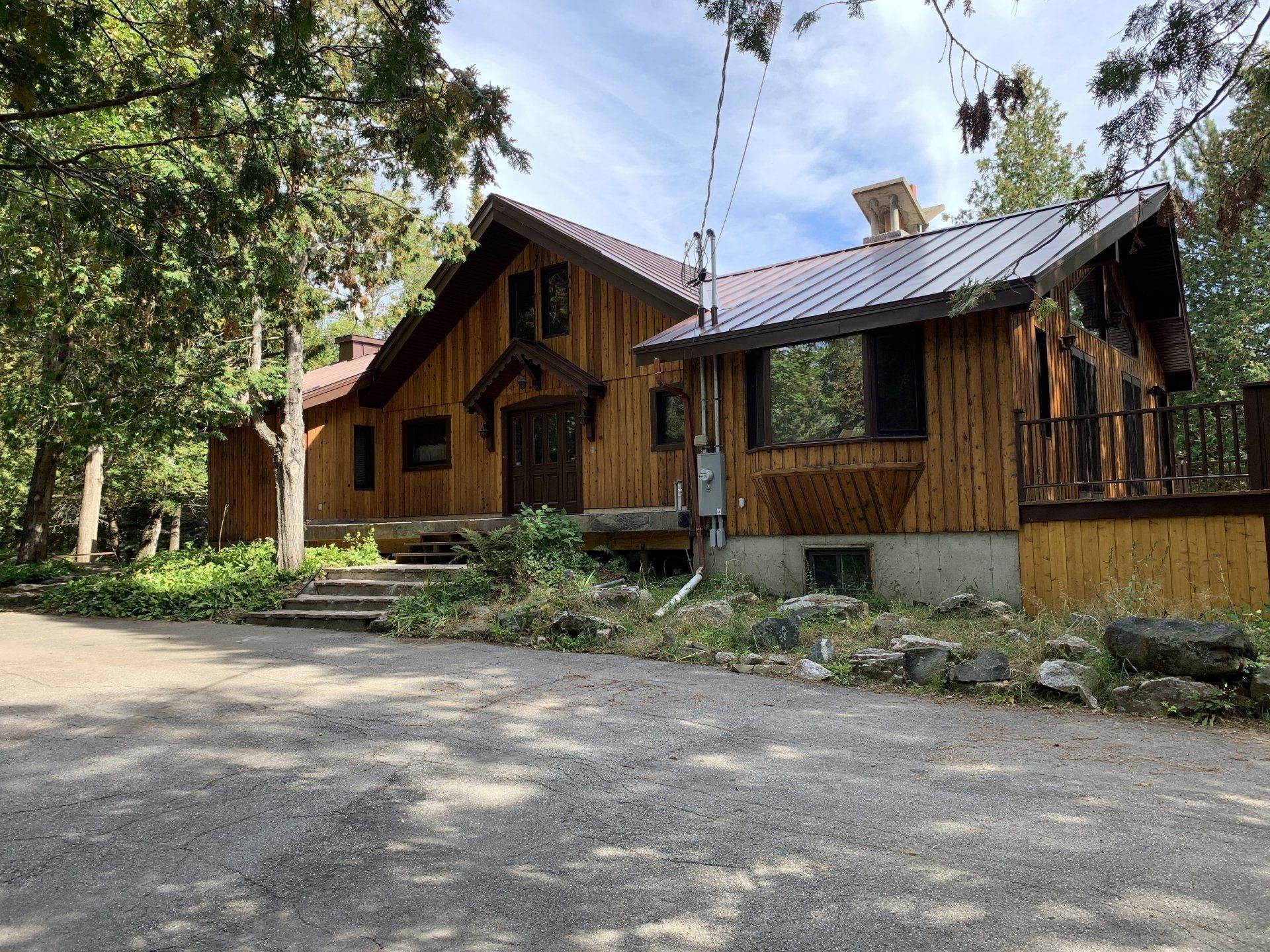 Une grande maison en bois avec un toit en métal est entourée d'arbres.