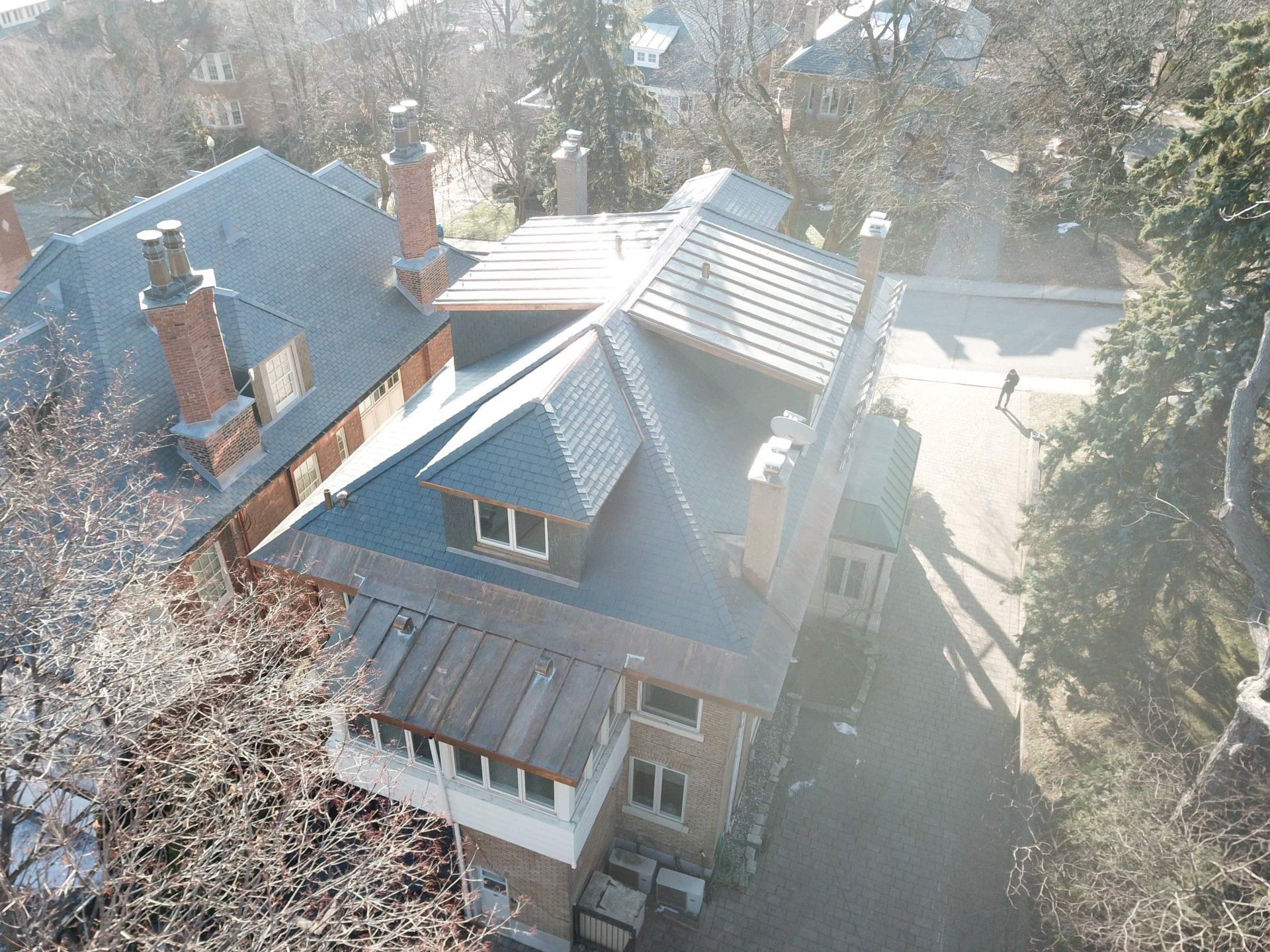 Une vue aérienne d'une maison au toit d'ardoise entourée d'arbres.
