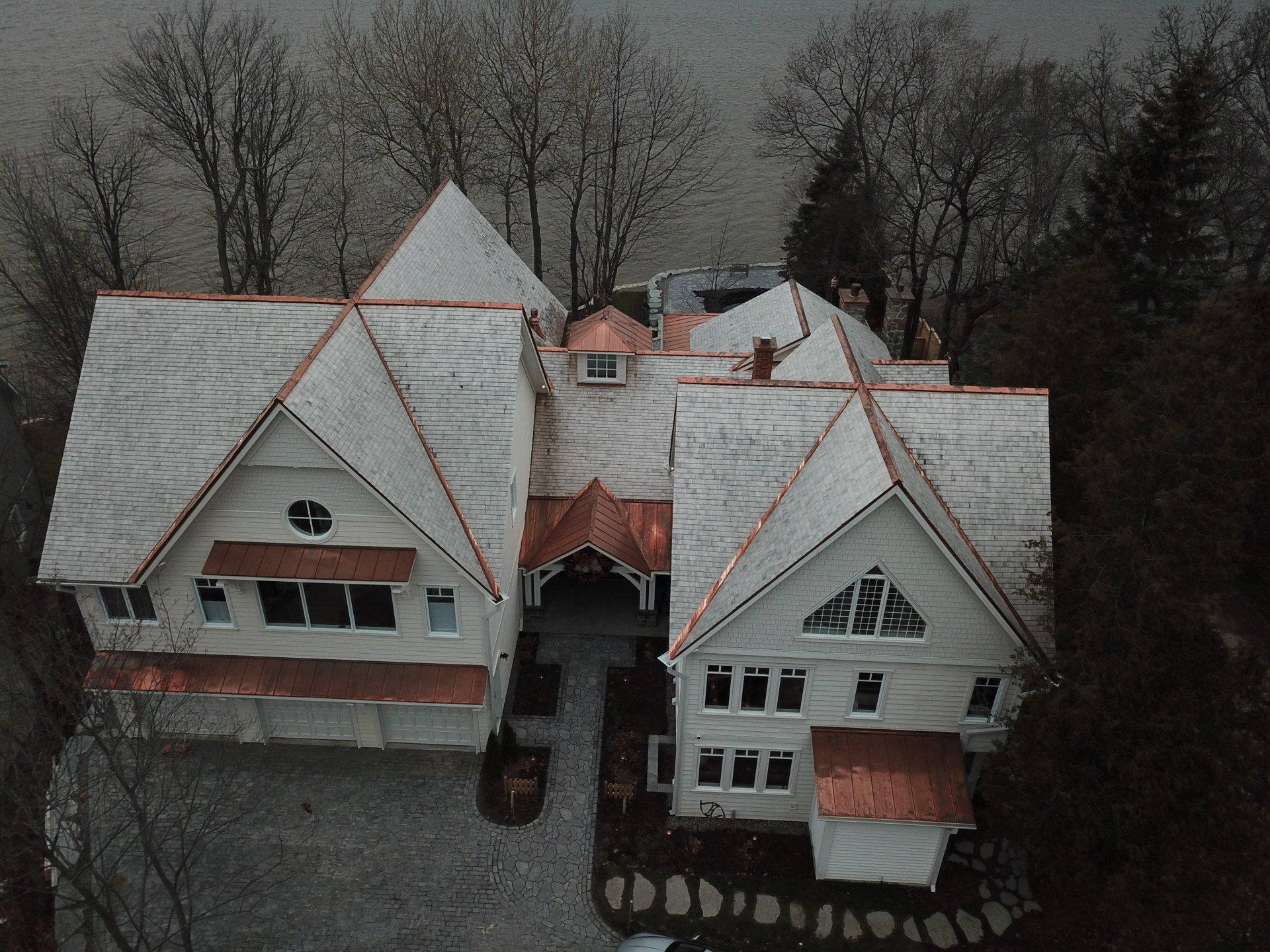 Une vue aérienne d'une grande maison blanche aux toits de cuivre entourée d'arbres.