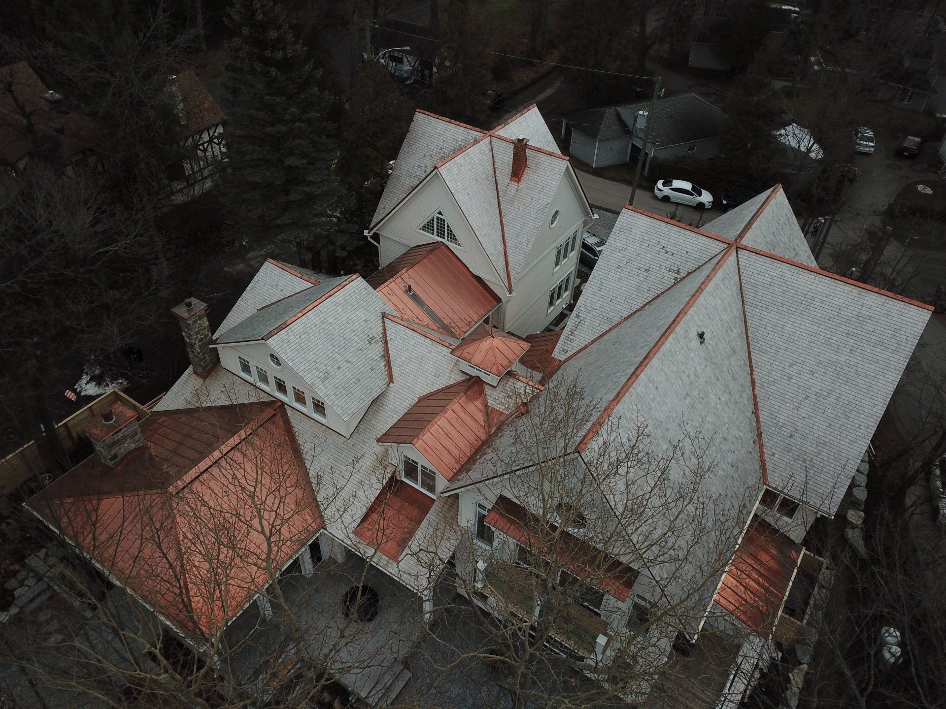 Une vue aérienne d'une grande maison au toit de cuivre entourée d'arbres.