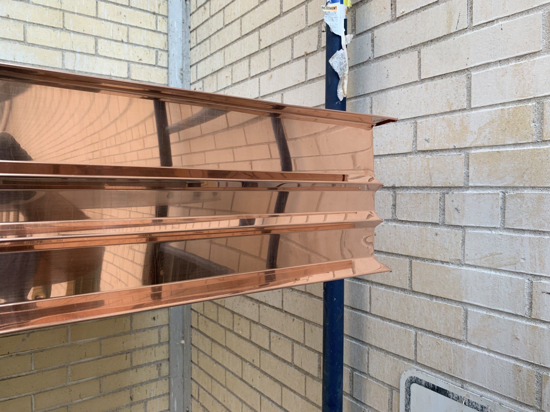 Un morceau de cuivre est accroché à un mur de briques.