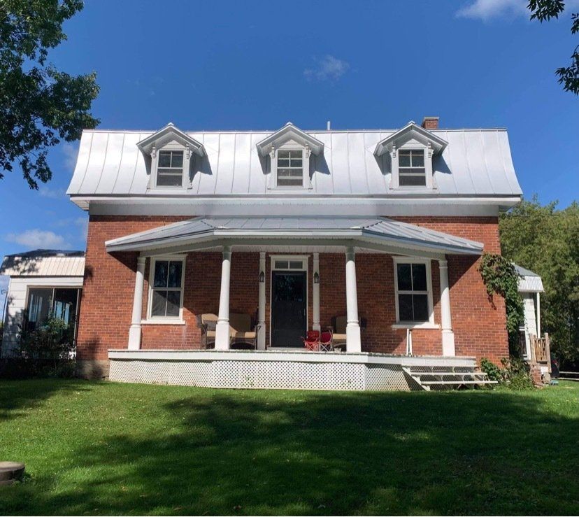 Une maison en brique avec un toit en métal et un porche