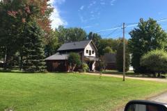 A house is sitting in the middle of a lush green field surrounded by trees.