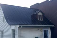 A white house with a black roof and a window.