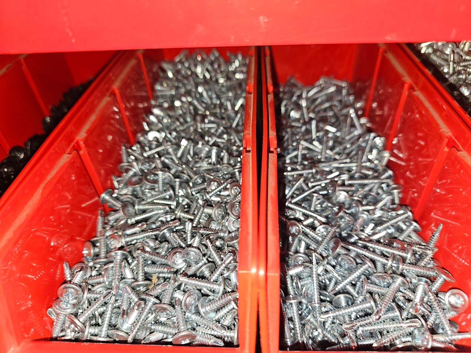 Dos contenedores rojos llenos de tornillos y tuercas