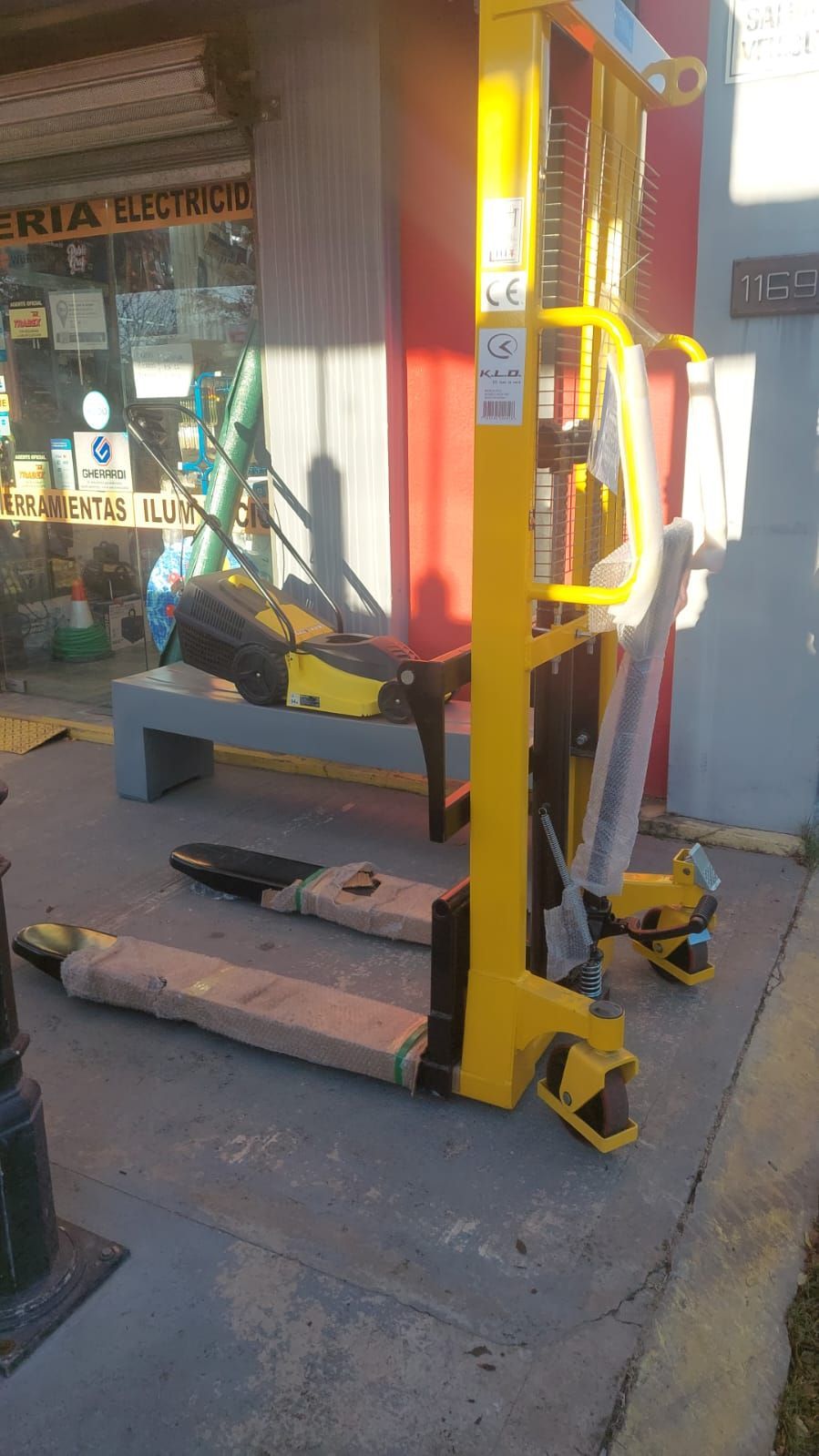 Una transpaleta amarilla está estacionada frente a un edificio.