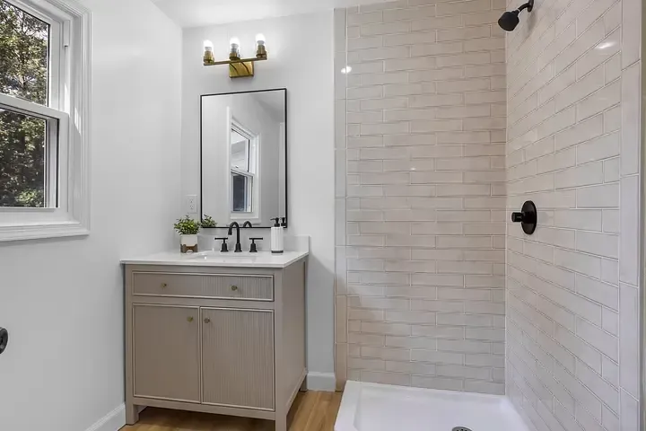 A bathroom with a sink , mirror , and walk in shower.