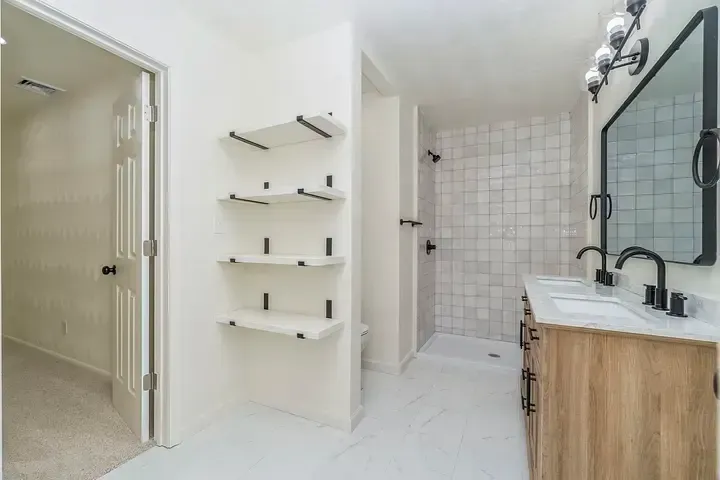 A bathroom with two sinks , a mirror , and a walk in shower.