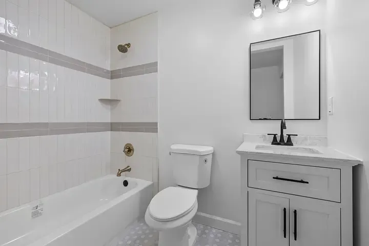A bathroom with a toilet , sink , bathtub and mirror.