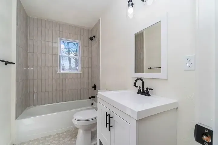 A bathroom with a sink , toilet , tub and mirror.