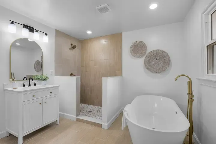 A bathroom with a tub , sink , mirror and walk in shower.