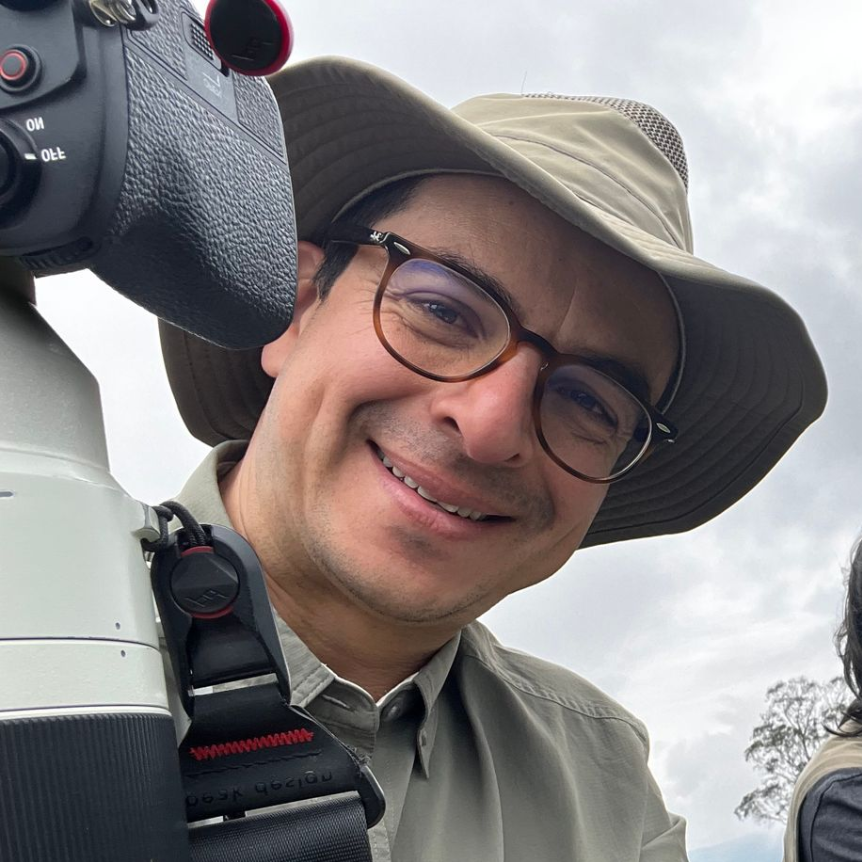A man wearing a hat and a jacket is taking a selfie
