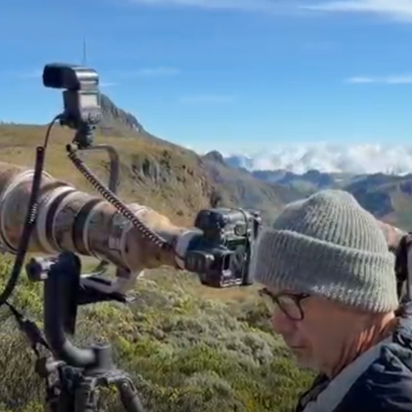Photographer with telephoto camera on a mountain overlook under a blue sky