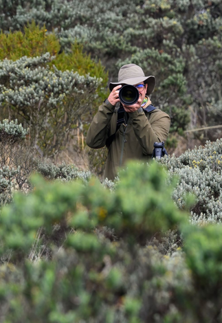 A man is taking a picture with a camera in a field.