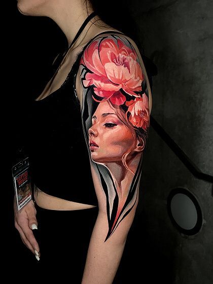 A woman has a tattoo of a woman 's face and flowers on her arm.