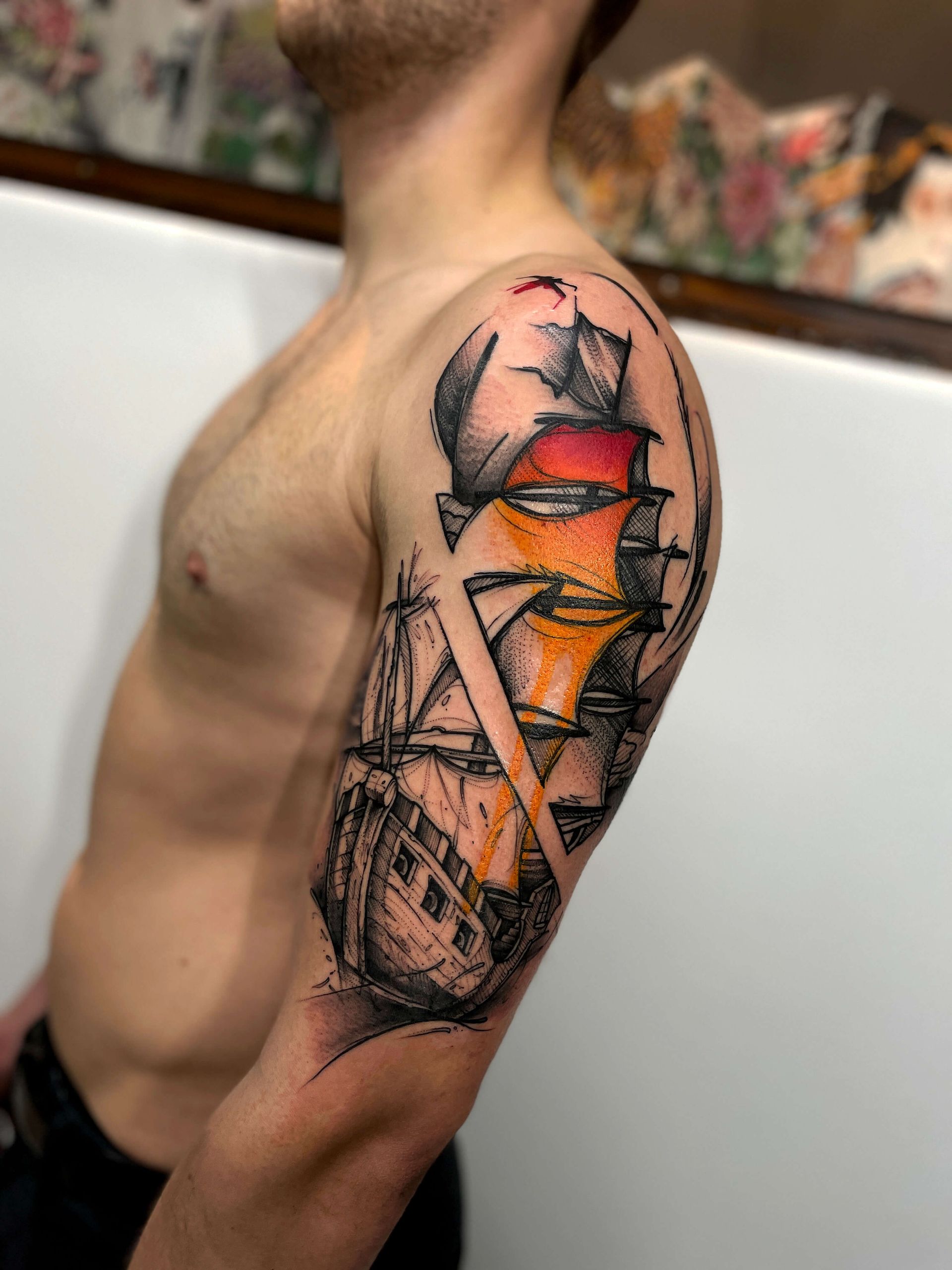 Männerarm mit farbenfrohem abstrakten Schiffstattoo, schwarzer Umrandung, orangefarbenen und roten Segeln.