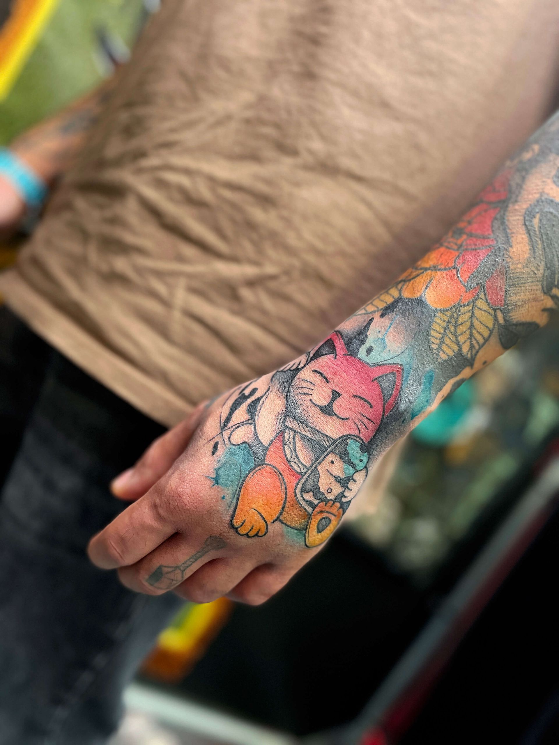 Buntes Cartoon-Katzentattoo auf Arm und Hand.