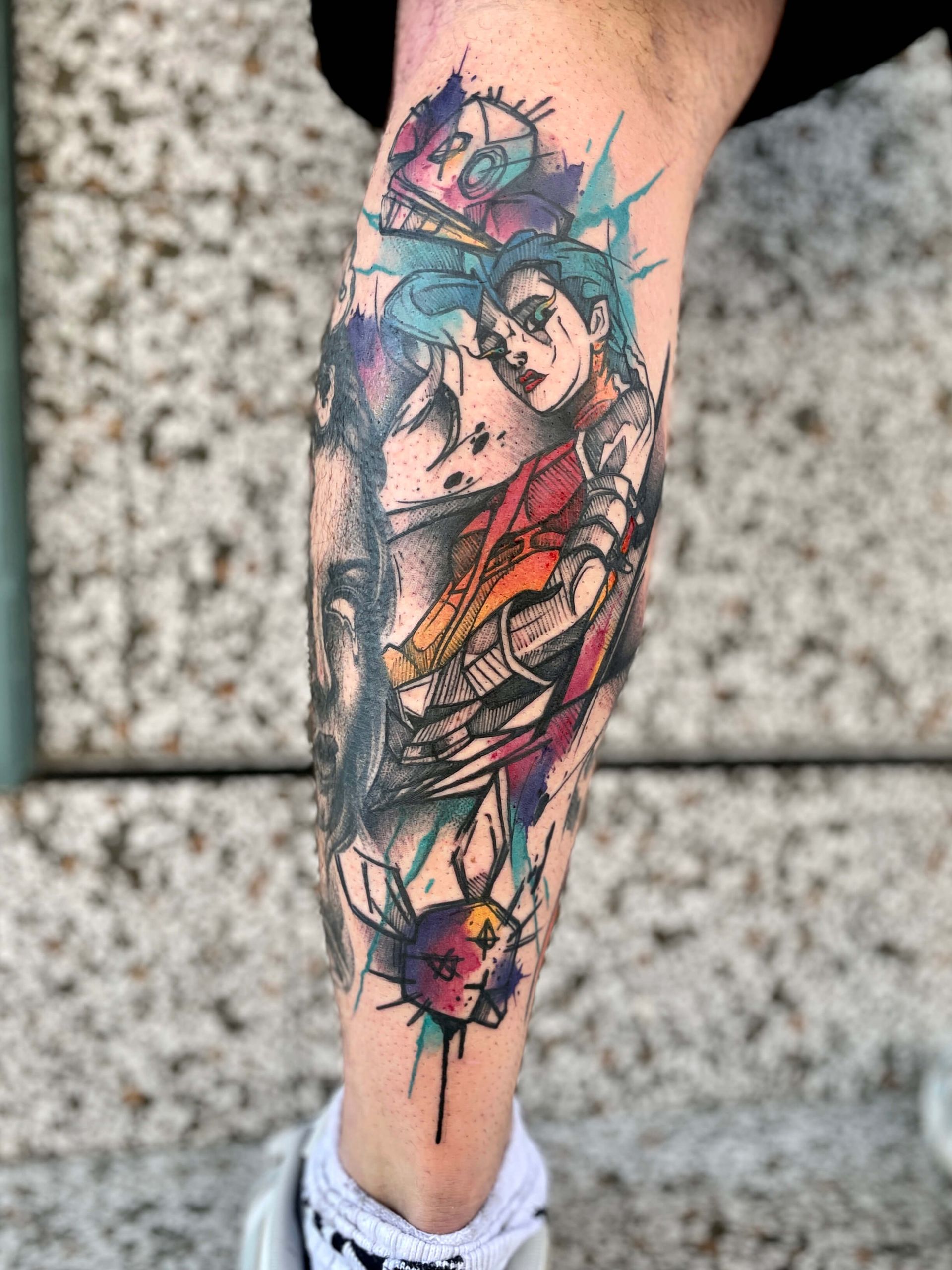 Tätowierung einer Person auf einem Bein mit farbenfrohen, stilisierten Figuren mit hellen Linien und Farbspritzern.