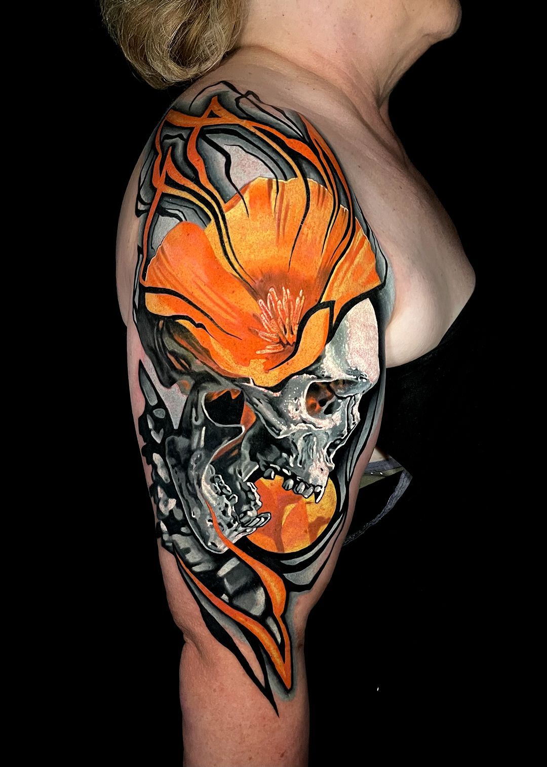 A woman has a tattoo of a skull and a flower on her arm.