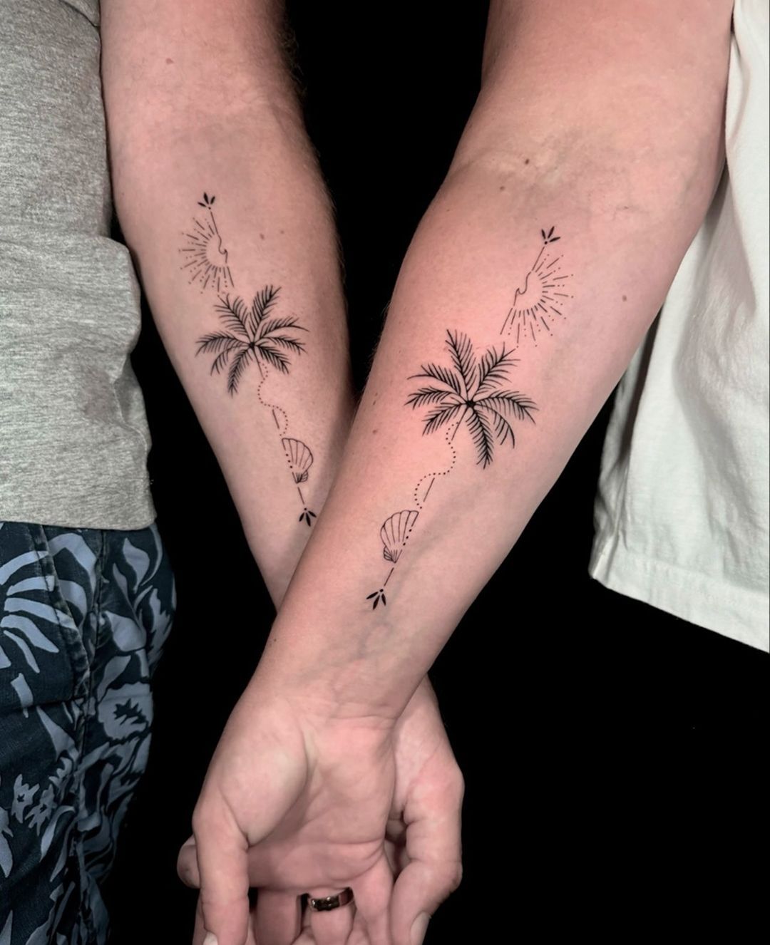 Two people with palm trees tattoos on their forearms