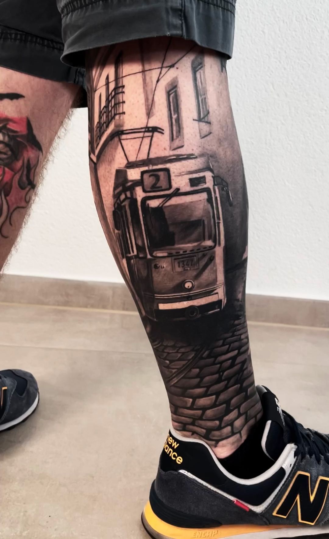 A man has a tattoo of a bus on his leg