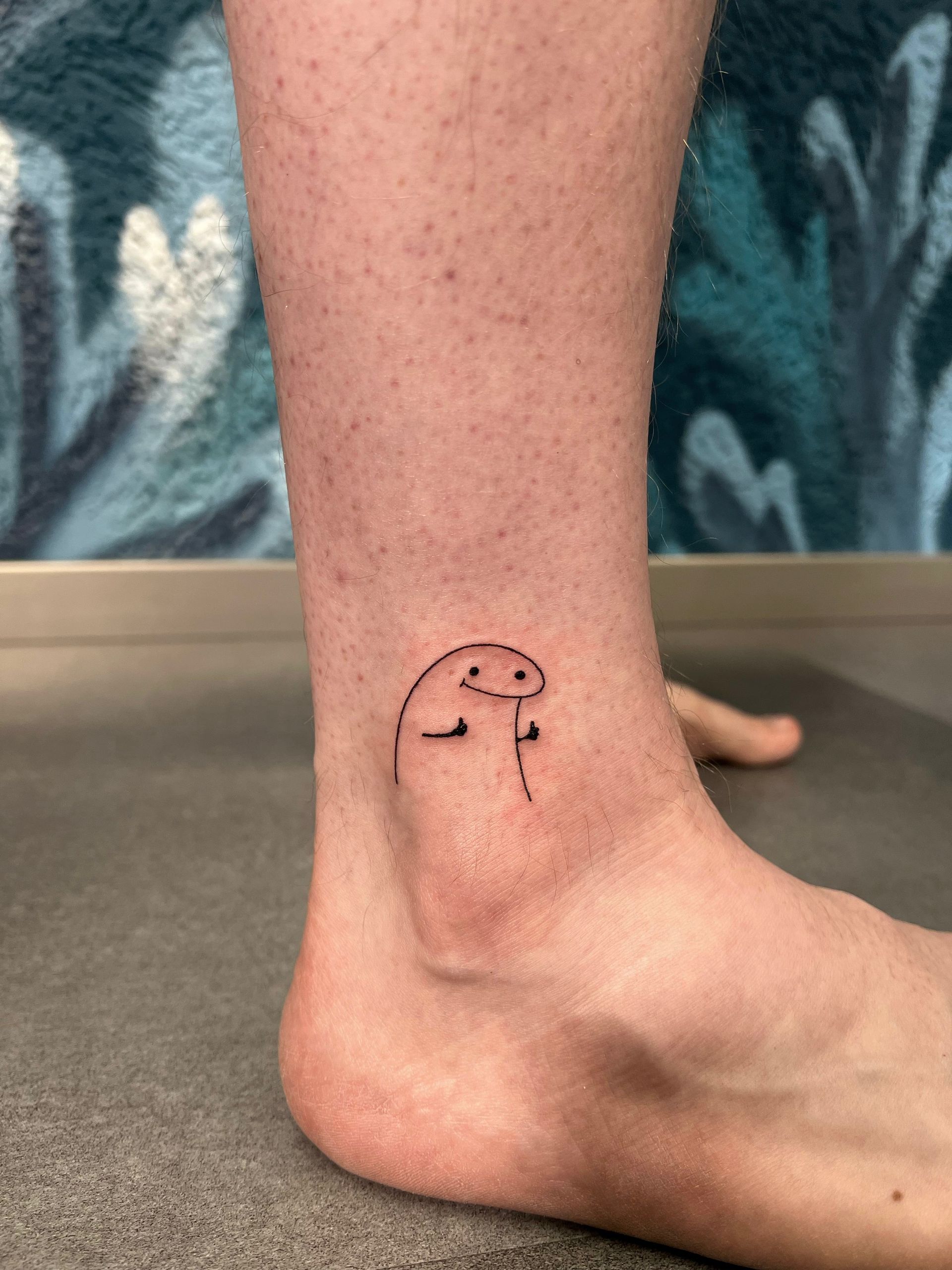A person has a small tattoo on their ankle.