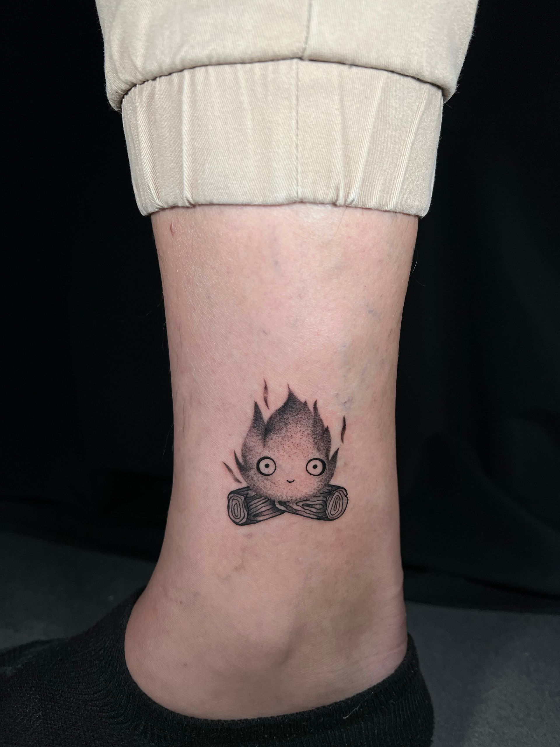A person has a small tattoo of a fire on their ankle