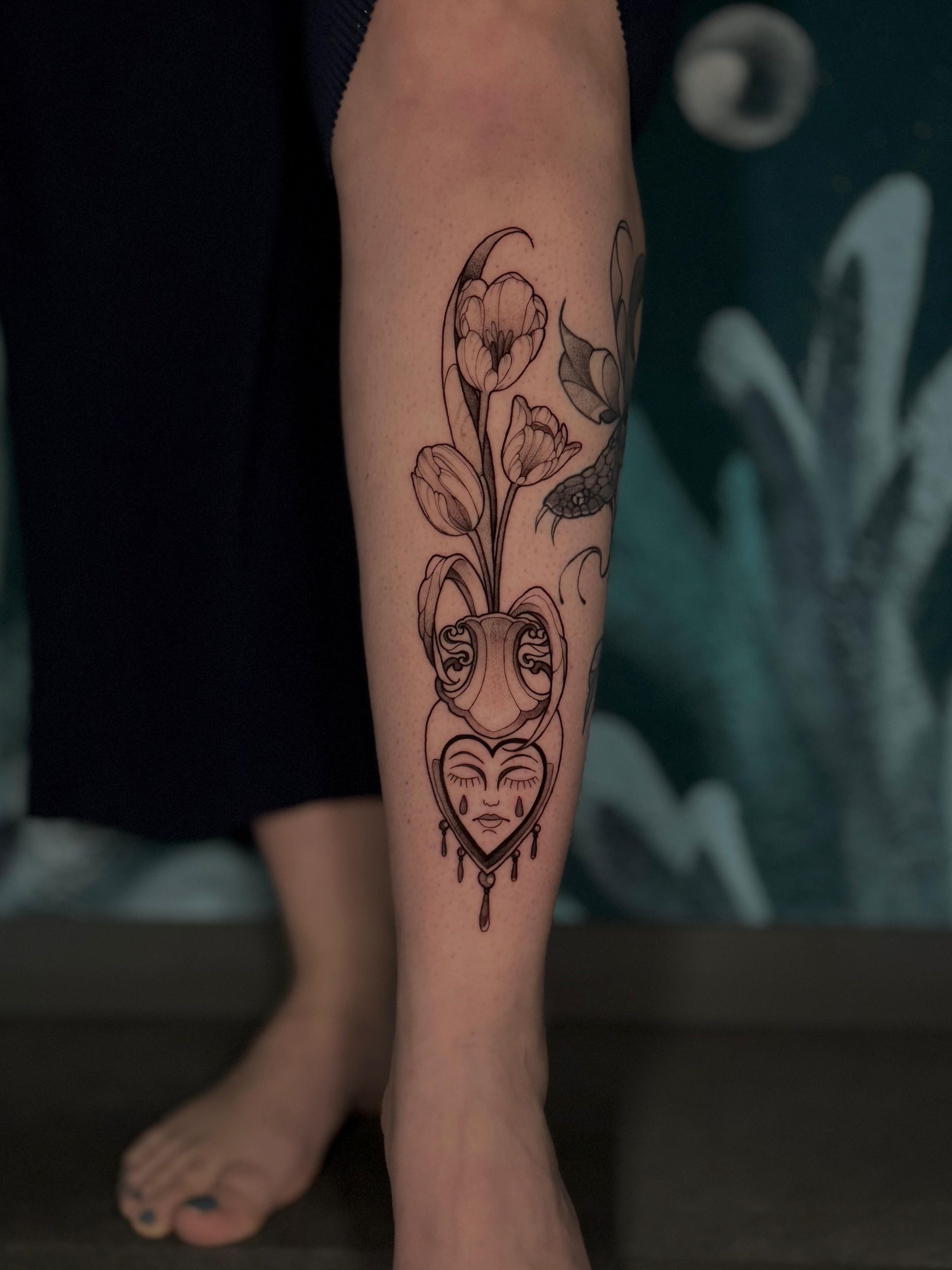 Eine Frau hat ein Tattoo mit einem Herzen und Blumen auf ihrem Bein.