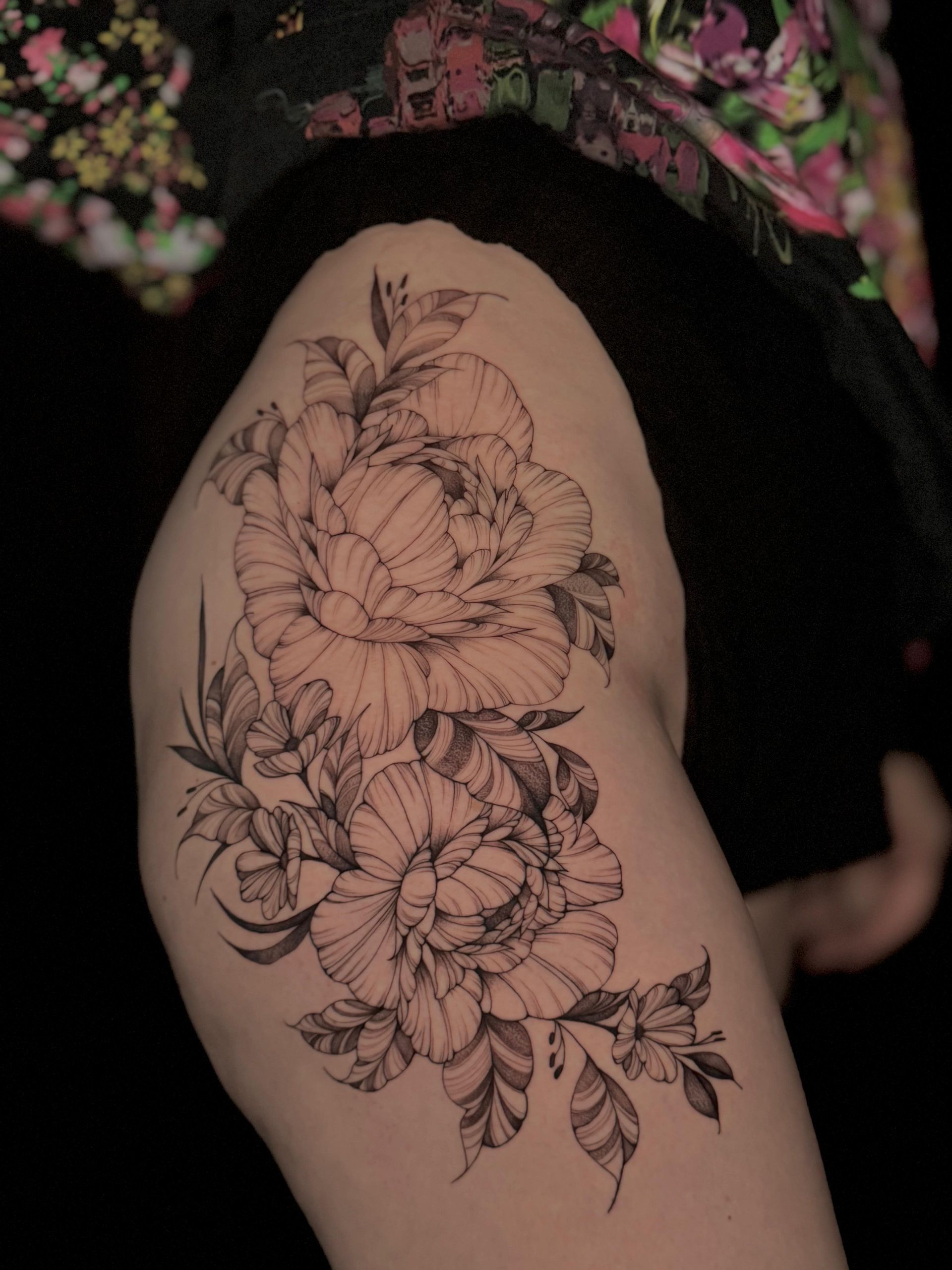 Eine Frau hat eine Blumentätowierung auf ihrem Oberschenkel