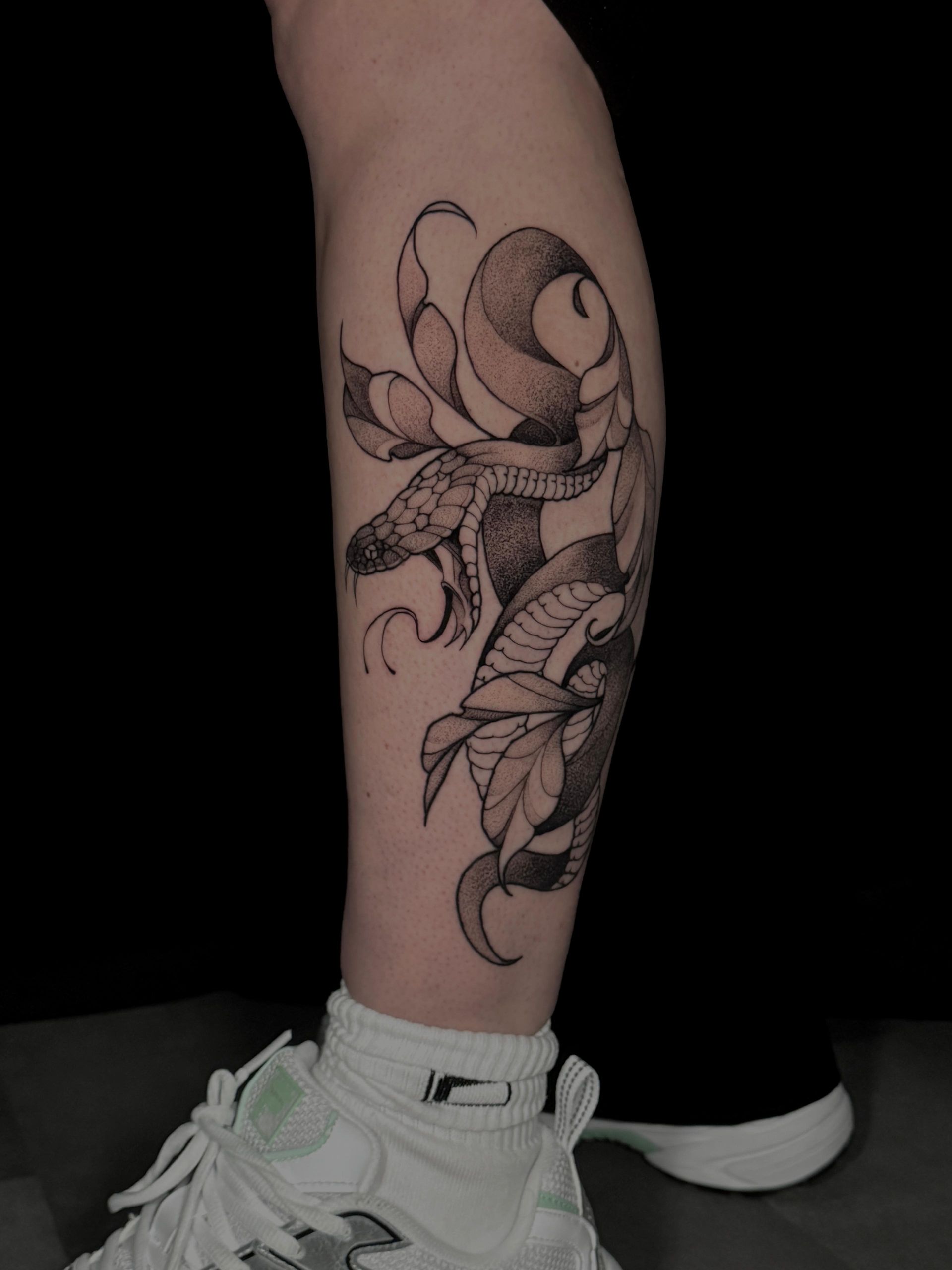 Eine Person hat eine Schlangentätowierung auf ihrem Bein.