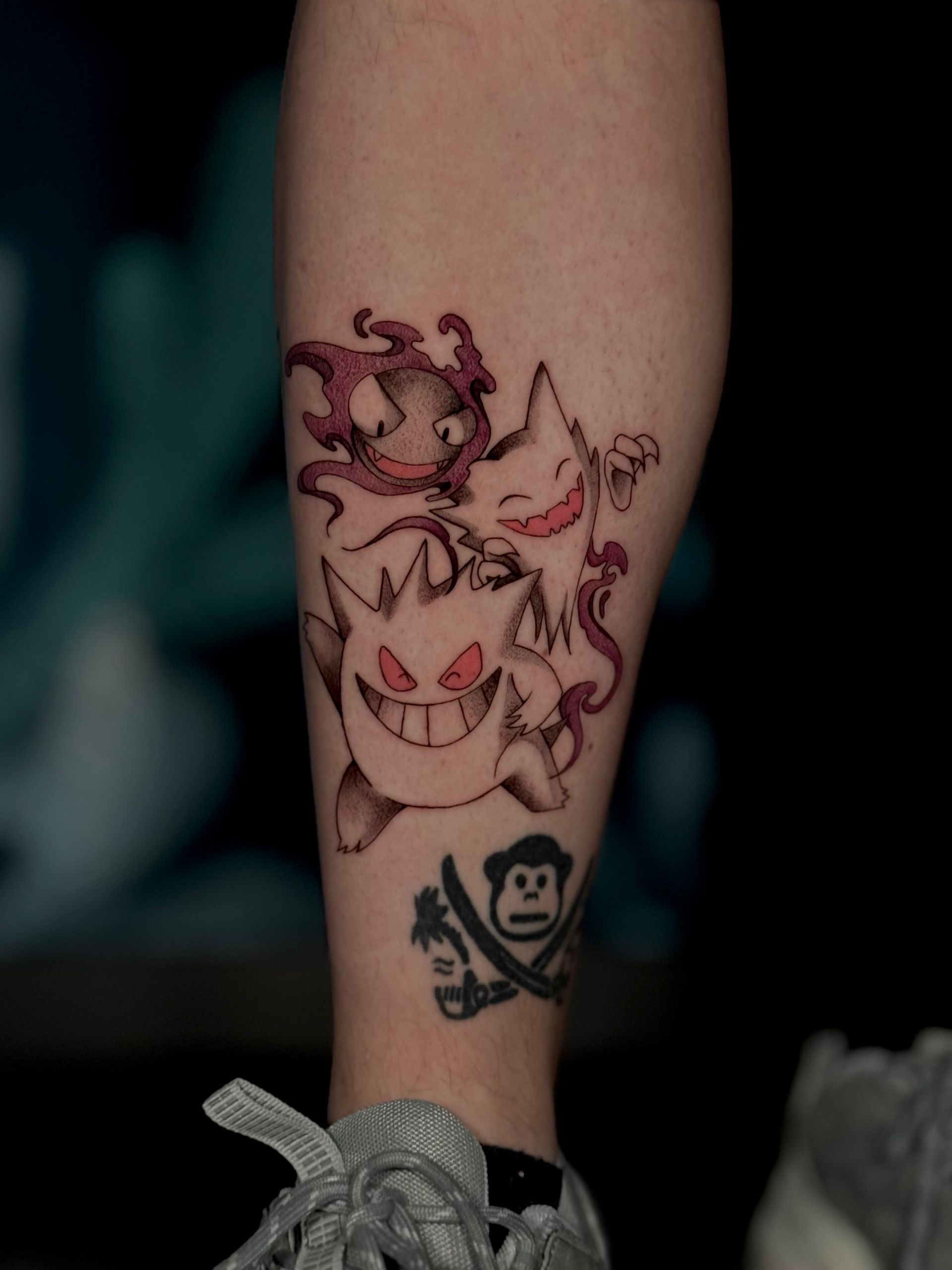 Eine Person hat eine Tätowierung einer Katze und eines Affen auf ihrem Bein