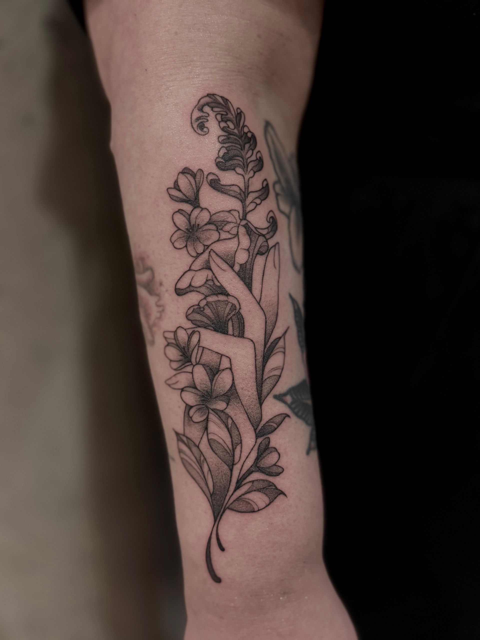 Eine Person hat eine Blumentätowierung auf dem Unterarm.