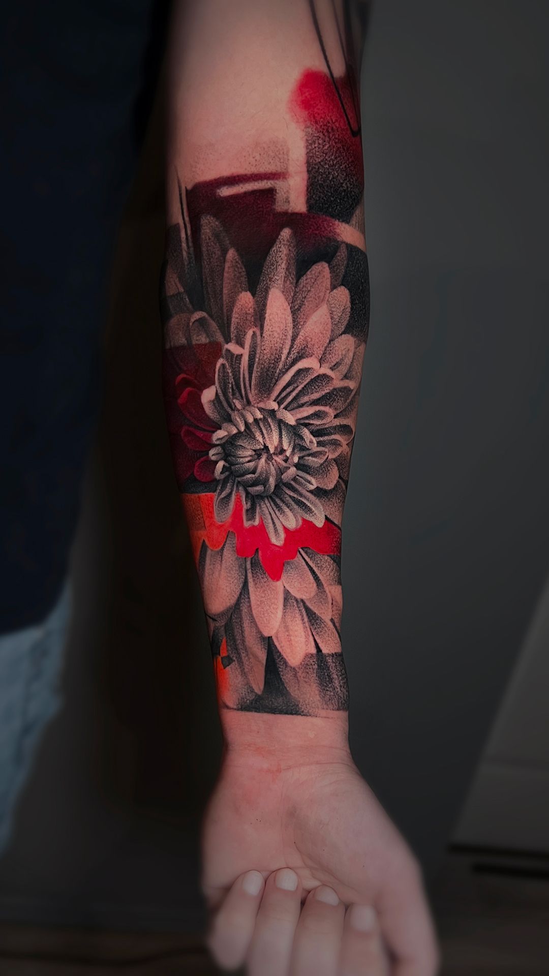A person has a tattoo of a flower on their forearm.