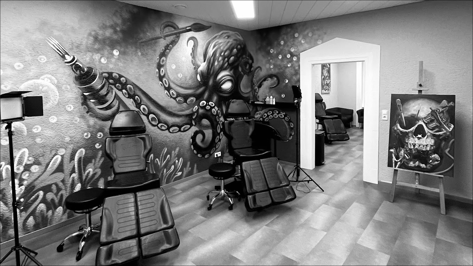 Schwarz-weißes Blumentattoo auf dem Arm einer Person, neben einem Button-Down-Hemd.